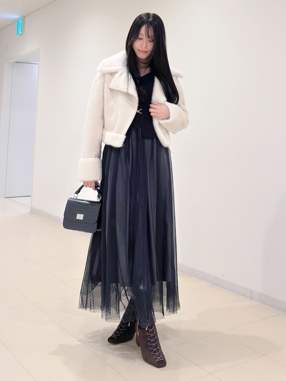 ブラウン系のブーツ、ブラック系のハンドバッグ、ブラック系のワンピースを着用したレディースの秋コーディネートの2枚目の写真