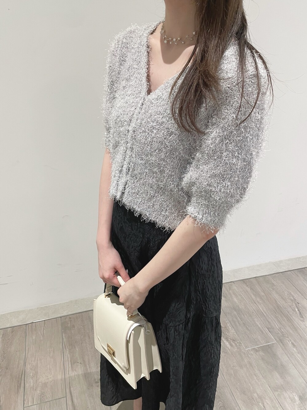 ブラック系のスカート、ホワイト系のパンプス、ホワイト系のカーディガン/ボレロを着用したレディースの冬コーディネートの5枚目の写真