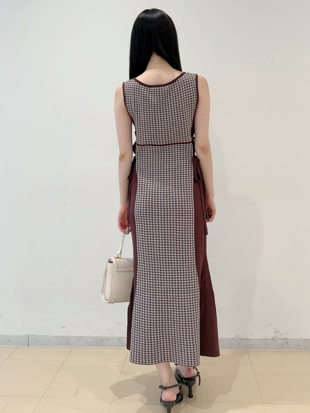 ブラウン系のワンピース、ホワイト系のハンドバッグ、グレー系のパンプスを着用したレディースの夏コーディネートの6枚目の写真