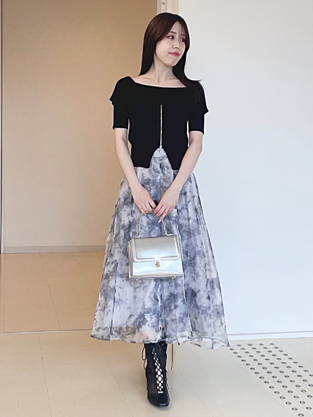 ブラック系のニット/セーター、グレー系のスカート、シルバー系のハンドバッグを着用したレディースの夏コーディネートの2枚目の写真