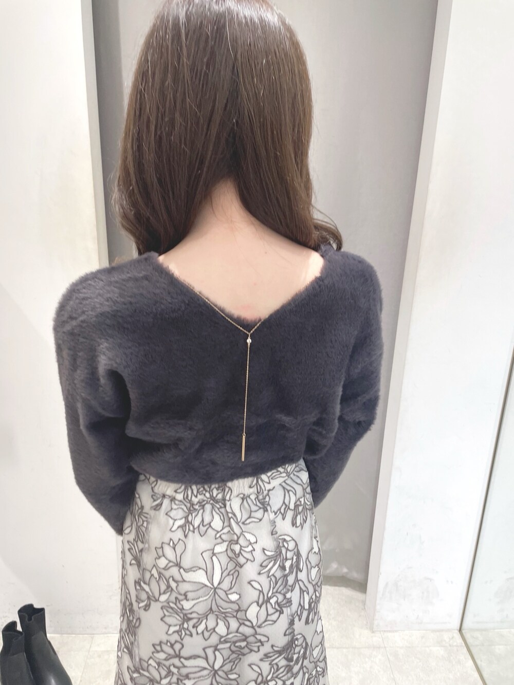 グレー系のニット/セーター、ホワイト系のスカート、ホワイト系のショルダーバッグを着用したレディースの秋コーディネートの5枚目の写真