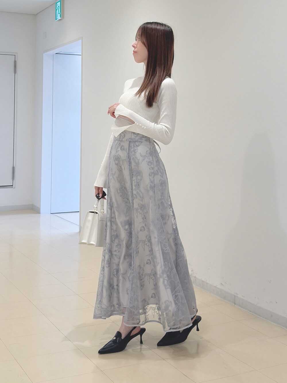 ホワイト系のニット/セーター、ブルー系のスカート、ホワイト系のハンドバッグを着用したレディースの冬コーディネートの3枚目の写真