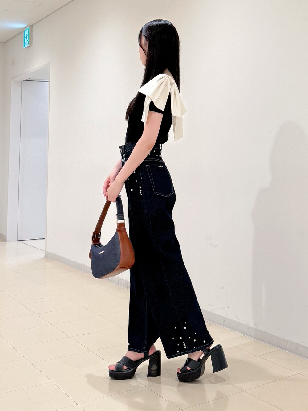 ブラック系のニット/セーター、ブルー系のデニムパンツ、ブルー系のショルダーバッグを着用したレディースの夏コーディネートの5枚目の写真