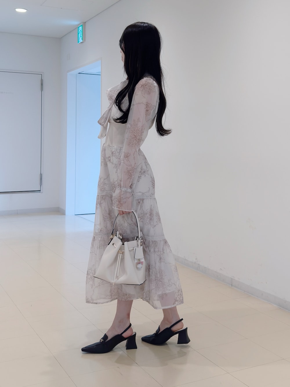 ベージュ系のワンピース、ホワイト系のショルダーバッグ、ブラウン系のパンプスを着用したレディースの冬コーディネートの3枚目の写真