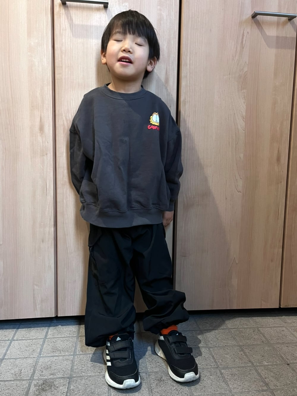 グレー系のトップス、ブラック系のカーゴパンツを着用したキッズの冬コーディネートの2枚目の写真