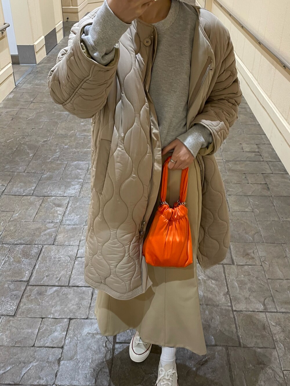 オレンジ系のバッグ、グレー系のスウェット、ホワイト系のスニーカーを着用したレディースの冬コーディネートの3枚目の写真