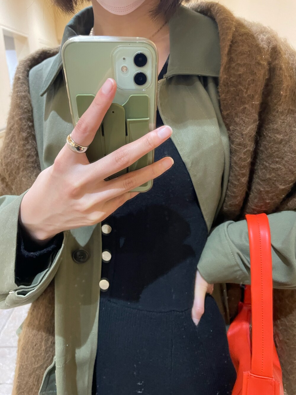 グリーン系のモッズコート、オレンジ系のショルダーバッグ、ベージュ系のブーツを着用したレディースの冬コーディネートの3枚目の写真