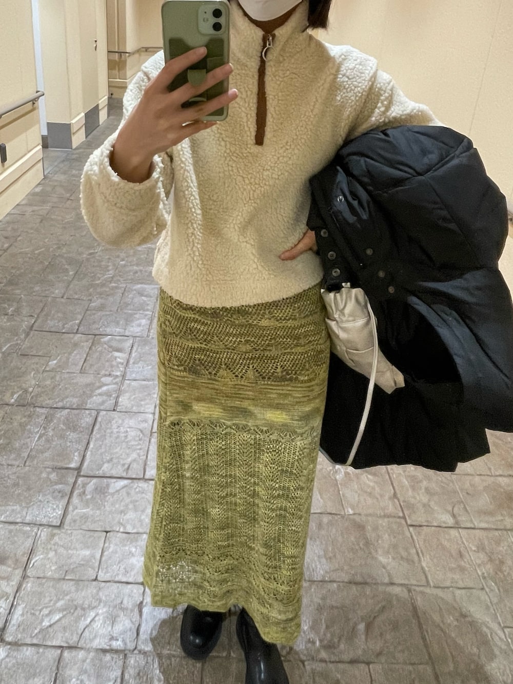 グリーン系のスカート、シルバー系のショルダーバッグ、ホワイト系のトップスを着用したレディースの冬コーディネートの2枚目の写真