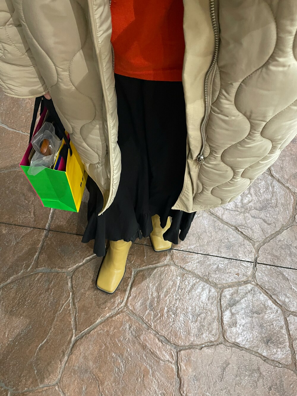 ブラック系のスカート、ホワイト系のその他アウター、ベージュ系のブーツを着用したレディースの冬コーディネートの2枚目の写真