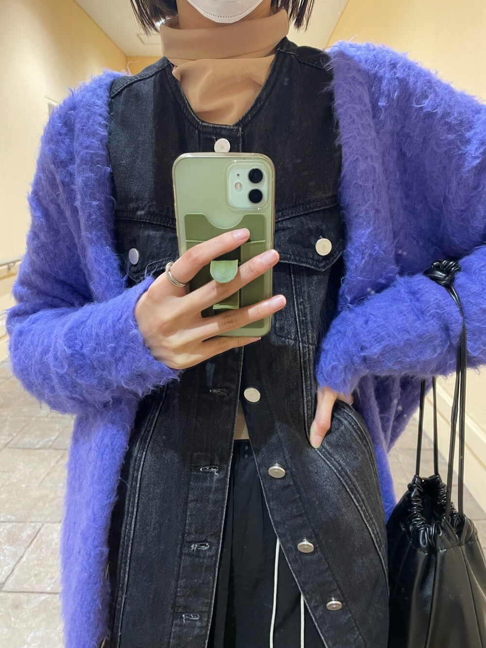 パープル系のカーディガン/ボレロ、ブラック系のスカート、ホワイト系のスニーカーを着用したレディースの冬コーディネートの2枚目の写真