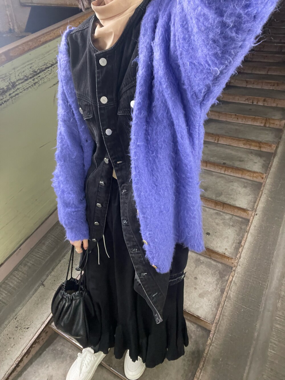 パープル系のカーディガン/ボレロ、ブラック系のスカート、ホワイト系のスニーカーを着用したレディースの冬コーディネートの3枚目の写真