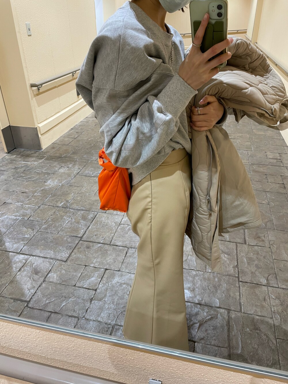 オレンジ系のバッグ、グレー系のスウェット、ホワイト系のスニーカーを着用したレディースの冬コーディネートの2枚目の写真