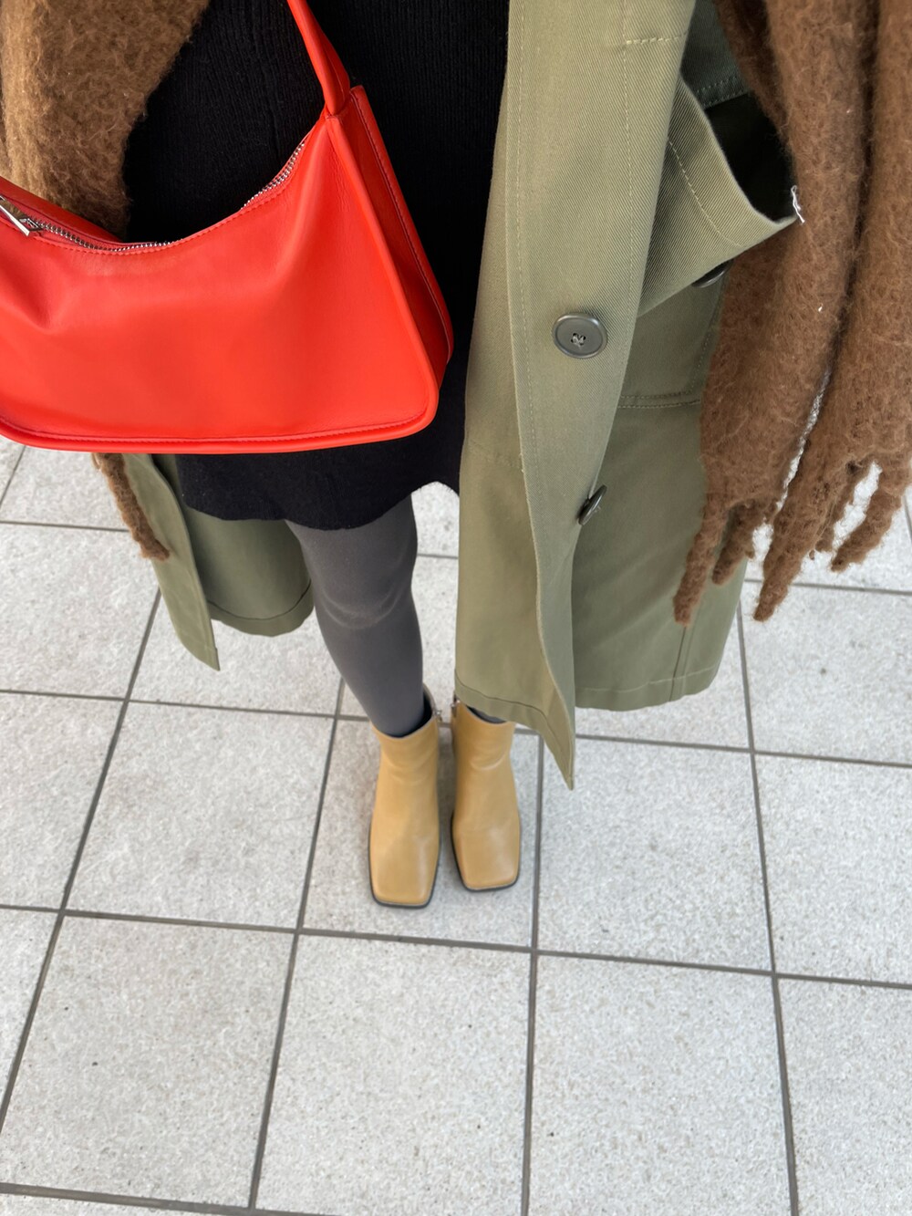 グリーン系のモッズコート、オレンジ系のショルダーバッグ、ベージュ系のブーツを着用したレディースの冬コーディネートの4枚目の写真