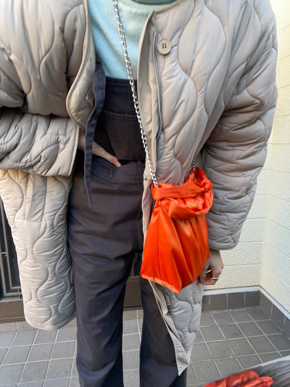 ホワイト系のスニーカー、ブラック系のサロペット/オーバーオール、オレンジ系のバッグを着用したレディースの冬コーディネートの3枚目の写真