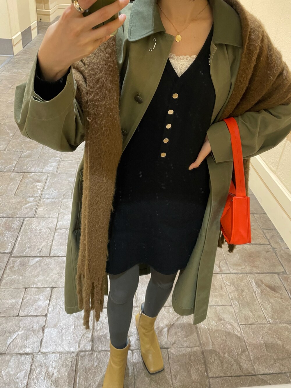 グリーン系のモッズコート、オレンジ系のショルダーバッグ、ベージュ系のブーツを着用したレディースの冬コーディネートの2枚目の写真