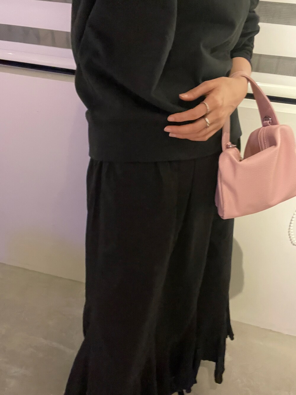 ブラック系のスカート、ピンク系のハンドバッグ、ブラック系のスウェットを着用したレディースの冬コーディネートの3枚目の写真