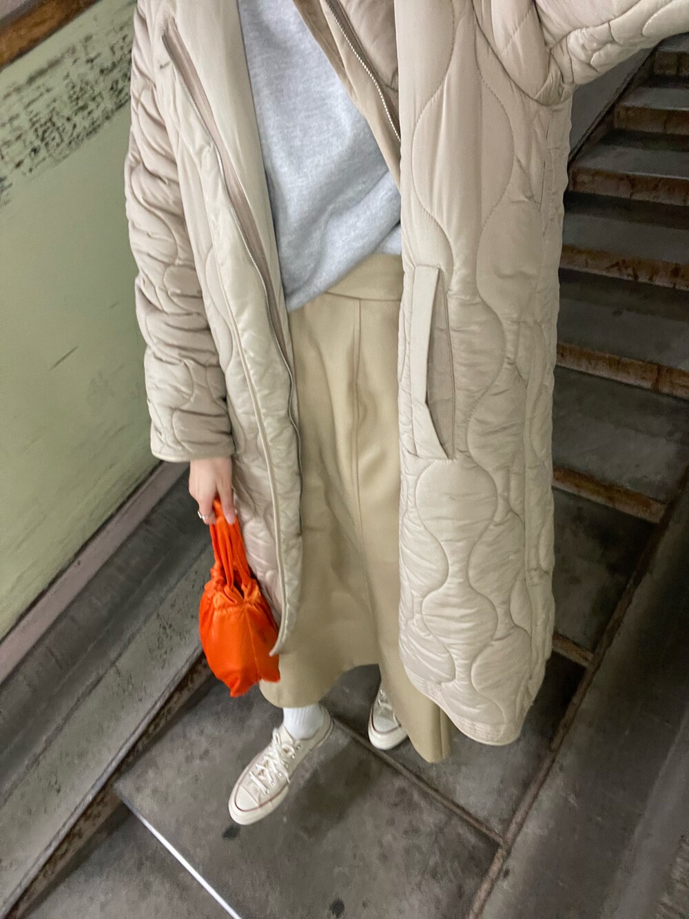 オレンジ系のバッグ、ホワイト系のスニーカー、ベージュ系のスカートを着用したレディースの冬コーディネートの3枚目の写真