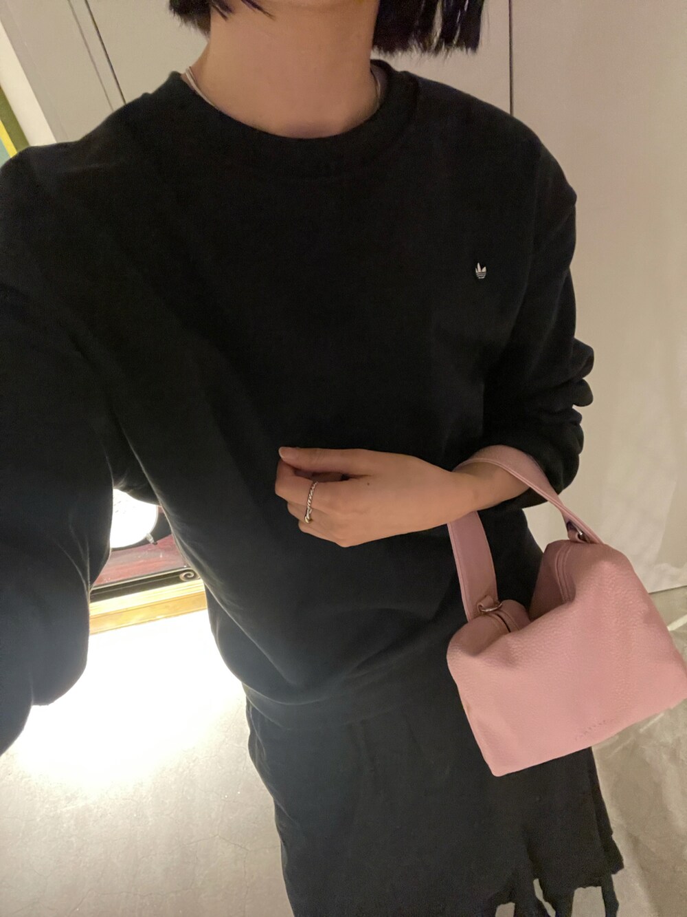 ブラック系のスカート、ピンク系のハンドバッグ、ブラック系のスウェットを着用したレディースの冬コーディネートの2枚目の写真