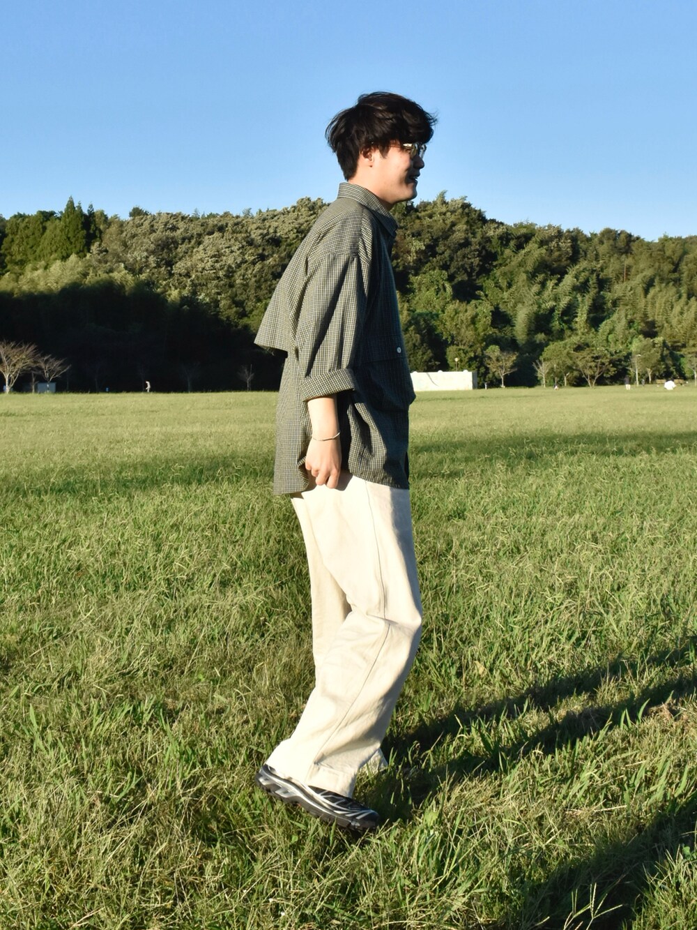 グリーン系のシャツ/ブラウス、ホワイト系のパンツ、ブラック系のスニーカーを着用したメンズの秋コーディネートの2枚目の写真
