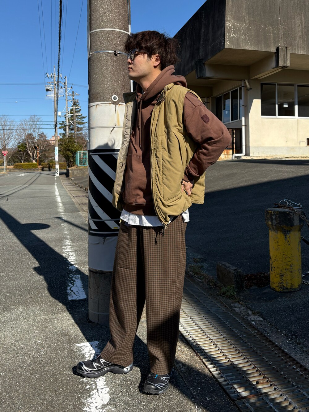 ブラック系のスニーカー、ブラウン系のパンツ、ベージュ系のダウンベストを着用したメンズの冬コーディネートの2枚目の写真