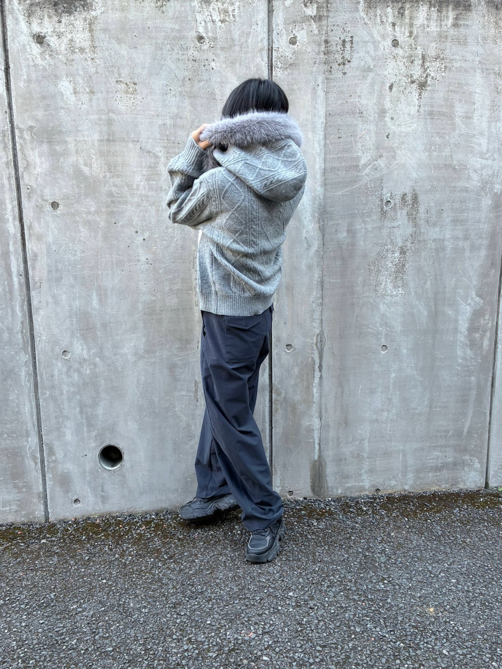 グレー系のニット/セーター、ブルー系のパンツ、ホワイト系のマフラーを着用したレディースの冬コーディネートの2枚目の写真