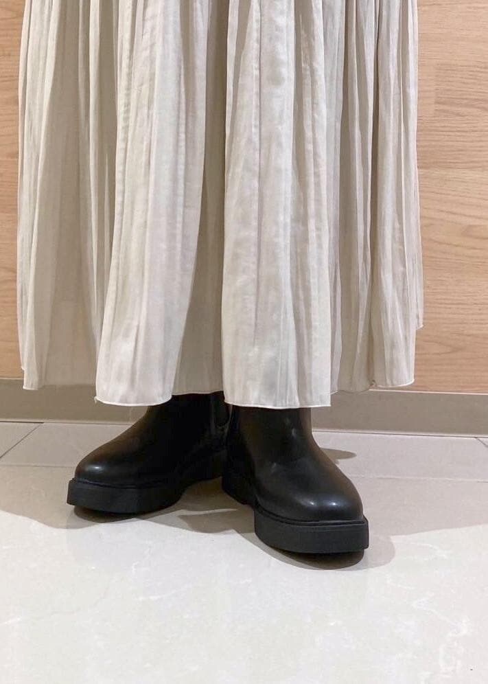 ベージュ系のスカート、ブラック系のブーツ、ブラック系のニット/セーターを着用したレディースの秋コーディネートの9枚目の写真