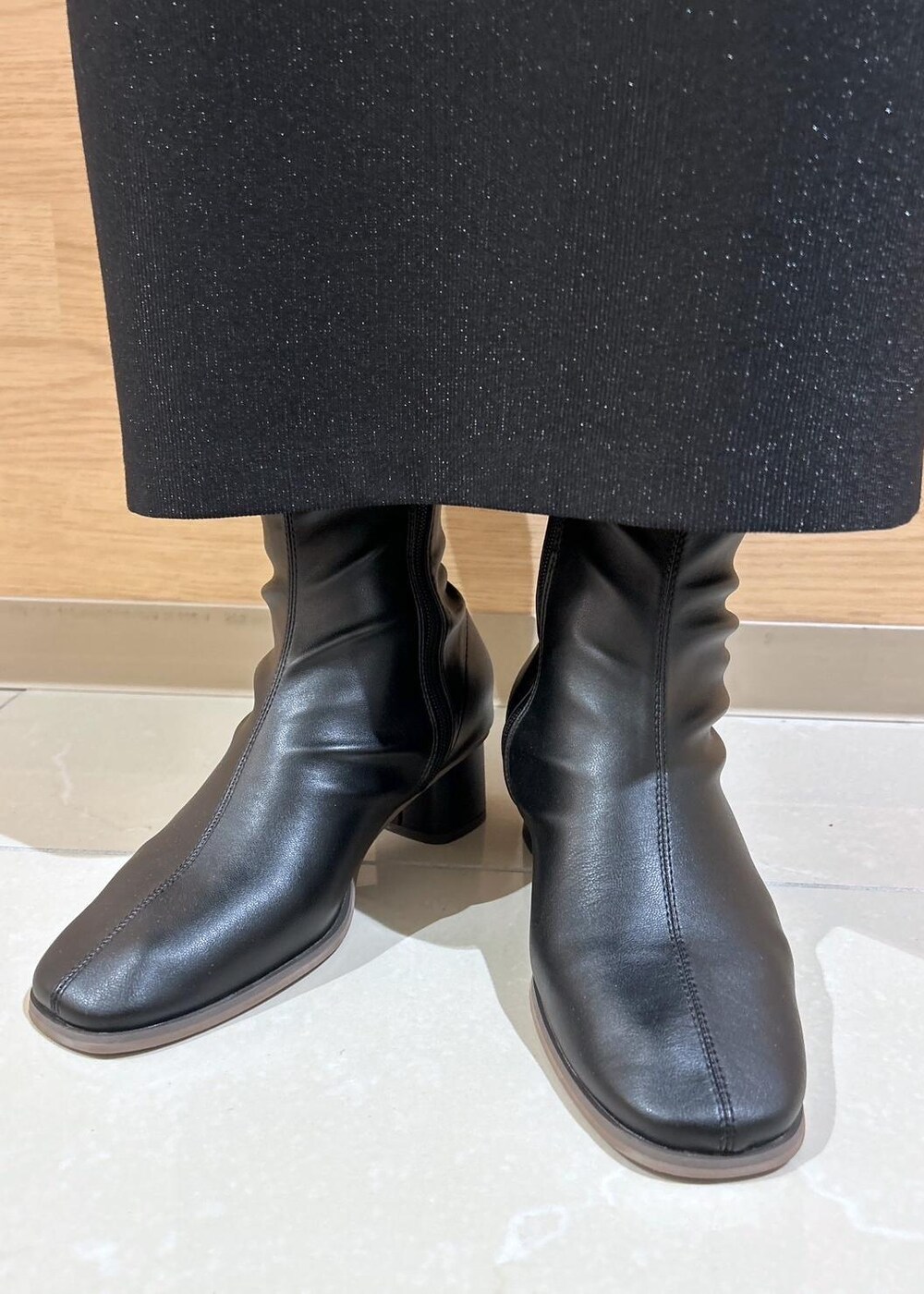 ブラック系のスカート、ブラウン系のマウンテンパーカー、ブラック系のブーツを着用したレディースの秋コーディネートの9枚目の写真