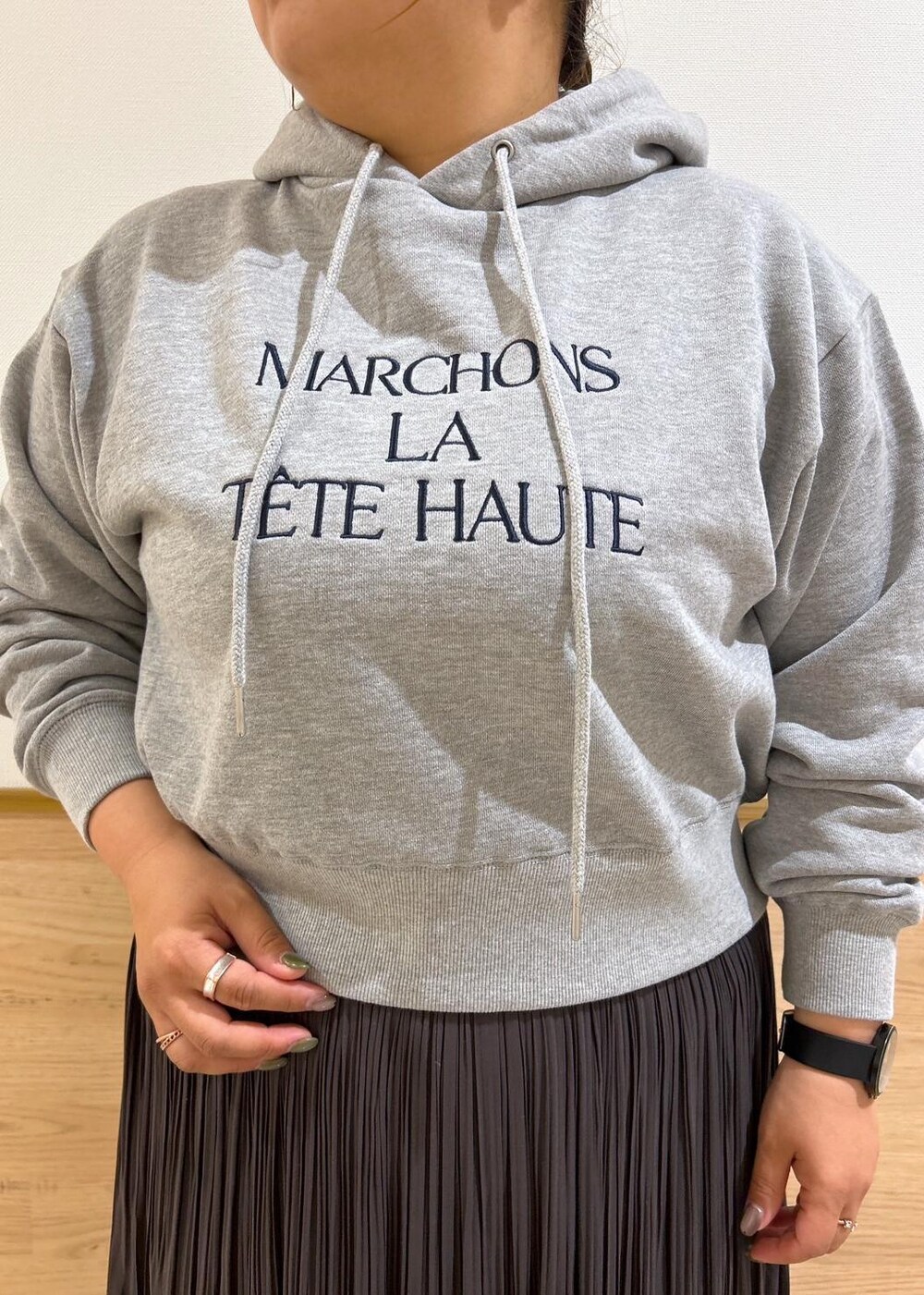 ブルー系のショルダーバッグ、ブラウン系のスカート、グレー系のパーカーを着用したレディースの秋コーディネートの4枚目の写真