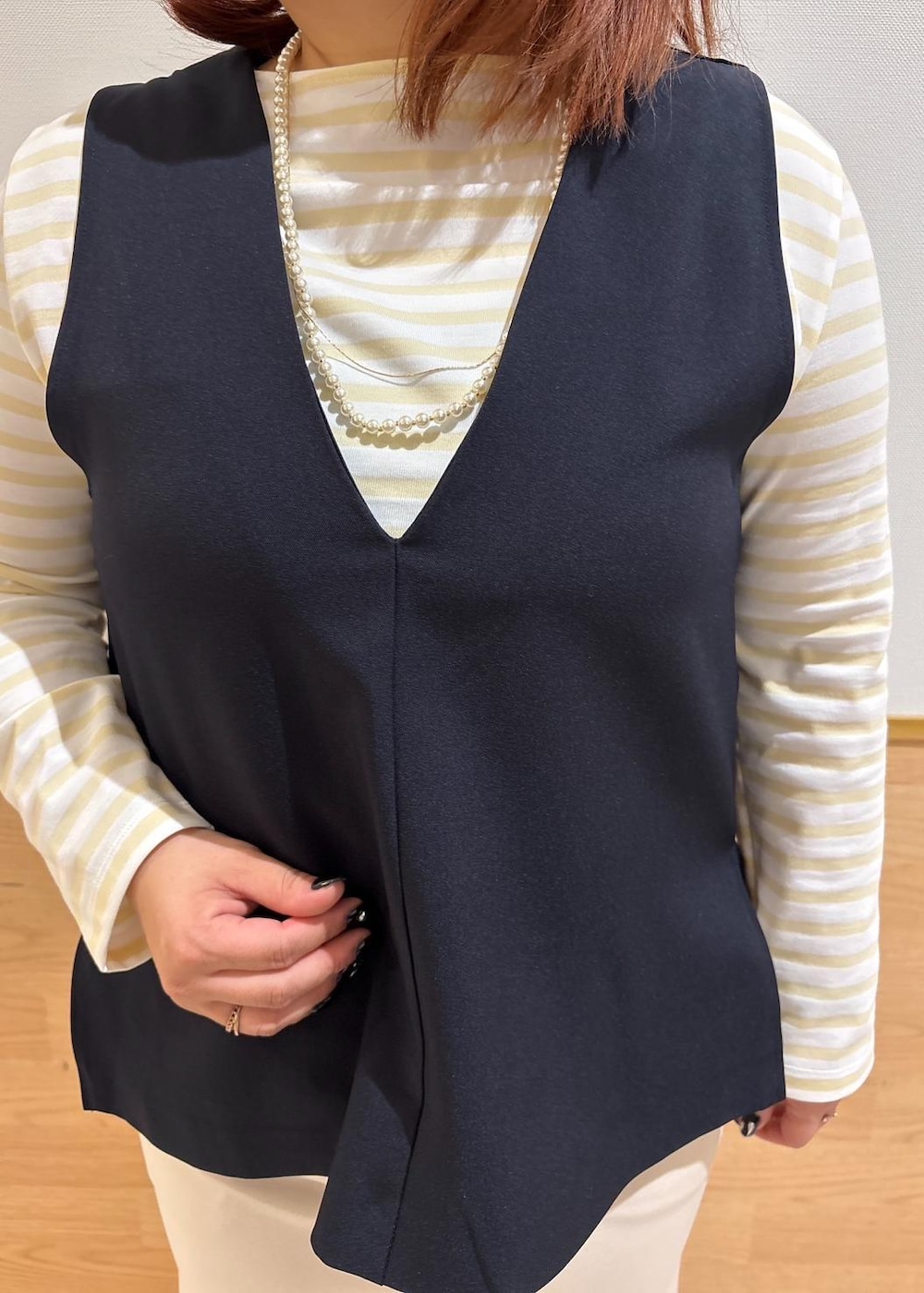 ベージュ系のスカート、ベージュ系のTシャツ/カットソー、ブルー系のベストを着用したレディースの冬コーディネートの4枚目の写真