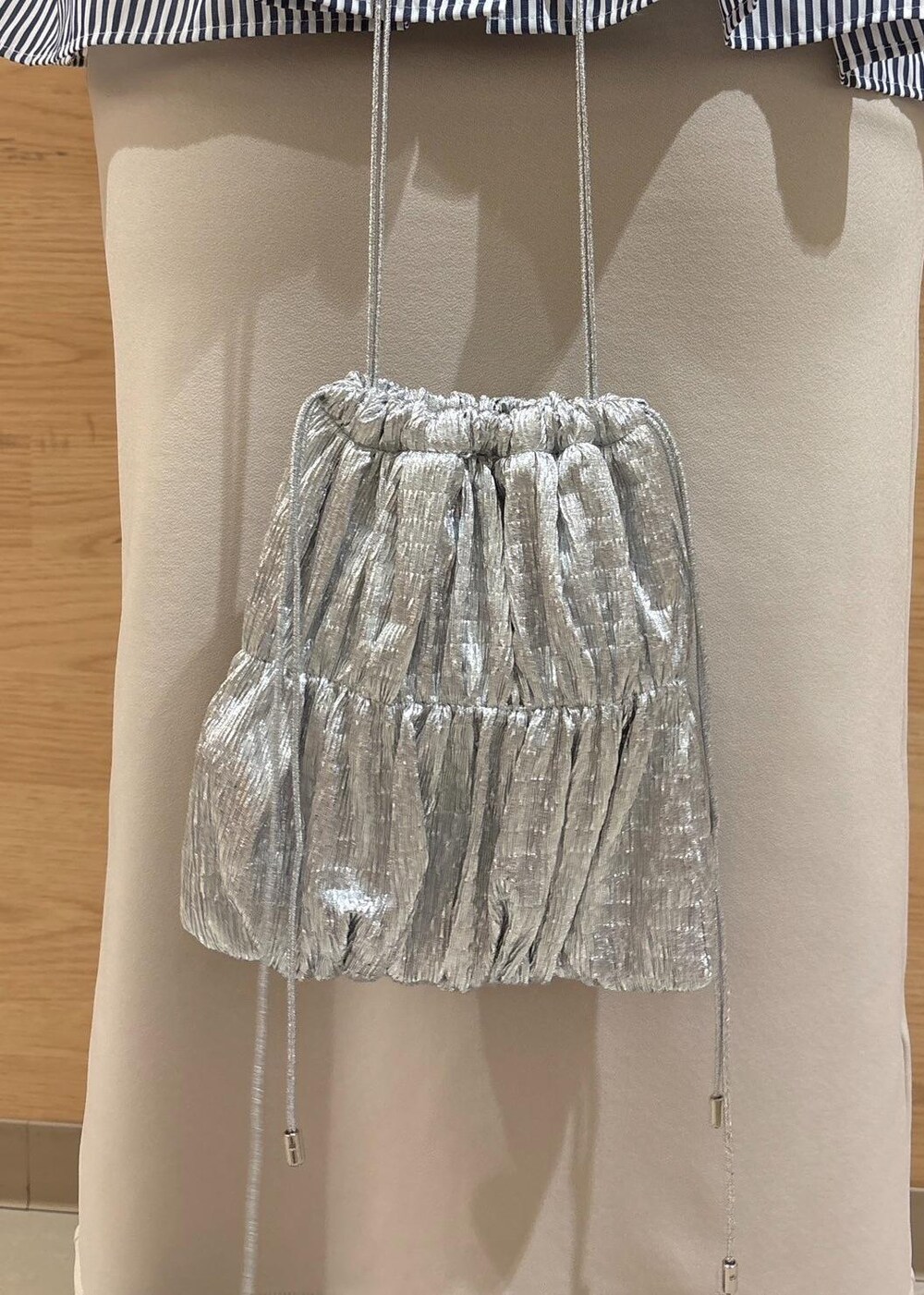 ベージュ系のスカート、ベージュ系のニット/セーター、シルバー系のショルダーバッグを着用したレディースの冬コーディネートの10枚目の写真