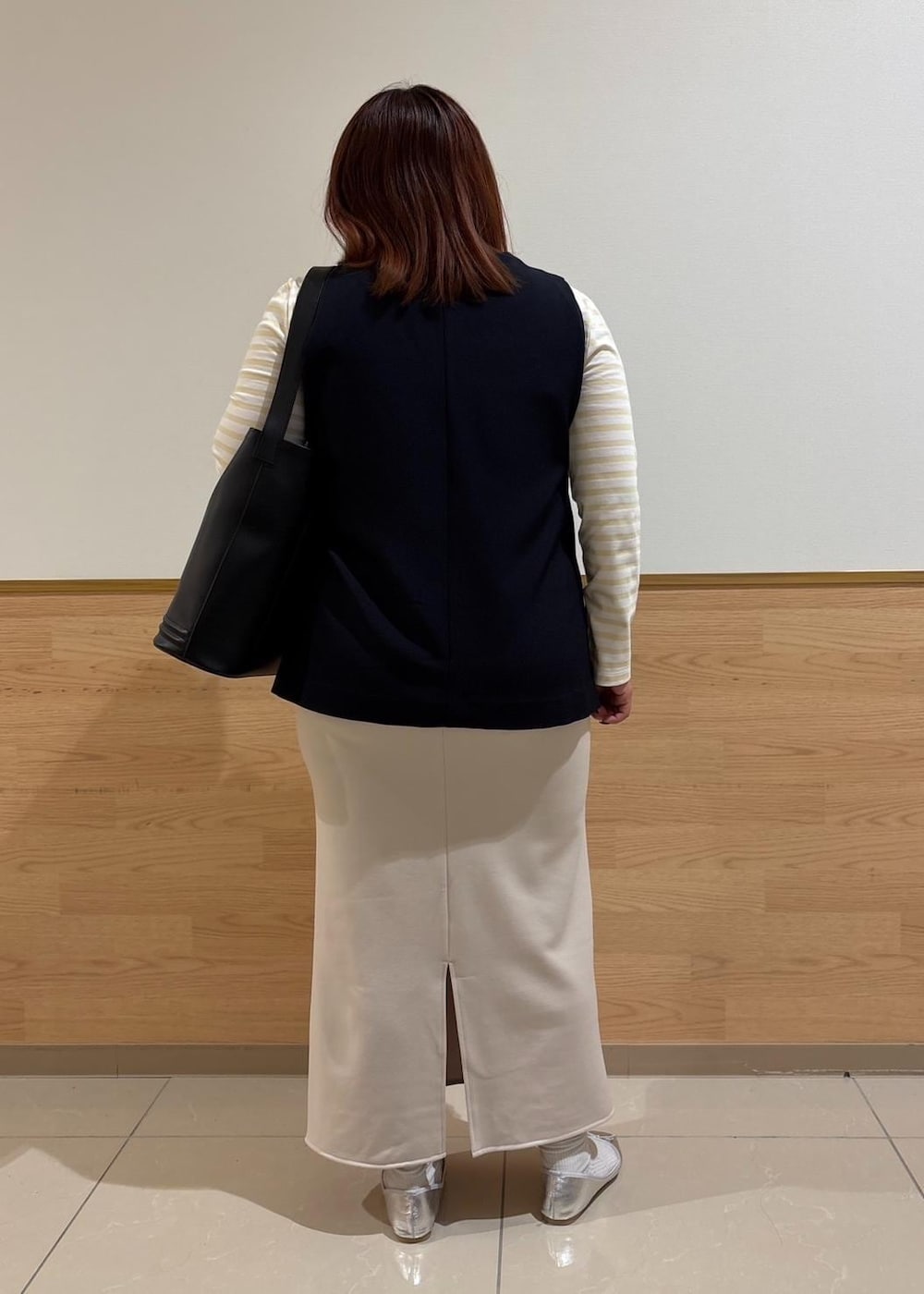 ベージュ系のスカート、ベージュ系のTシャツ/カットソー、ブルー系のベストを着用したレディースの冬コーディネートの3枚目の写真