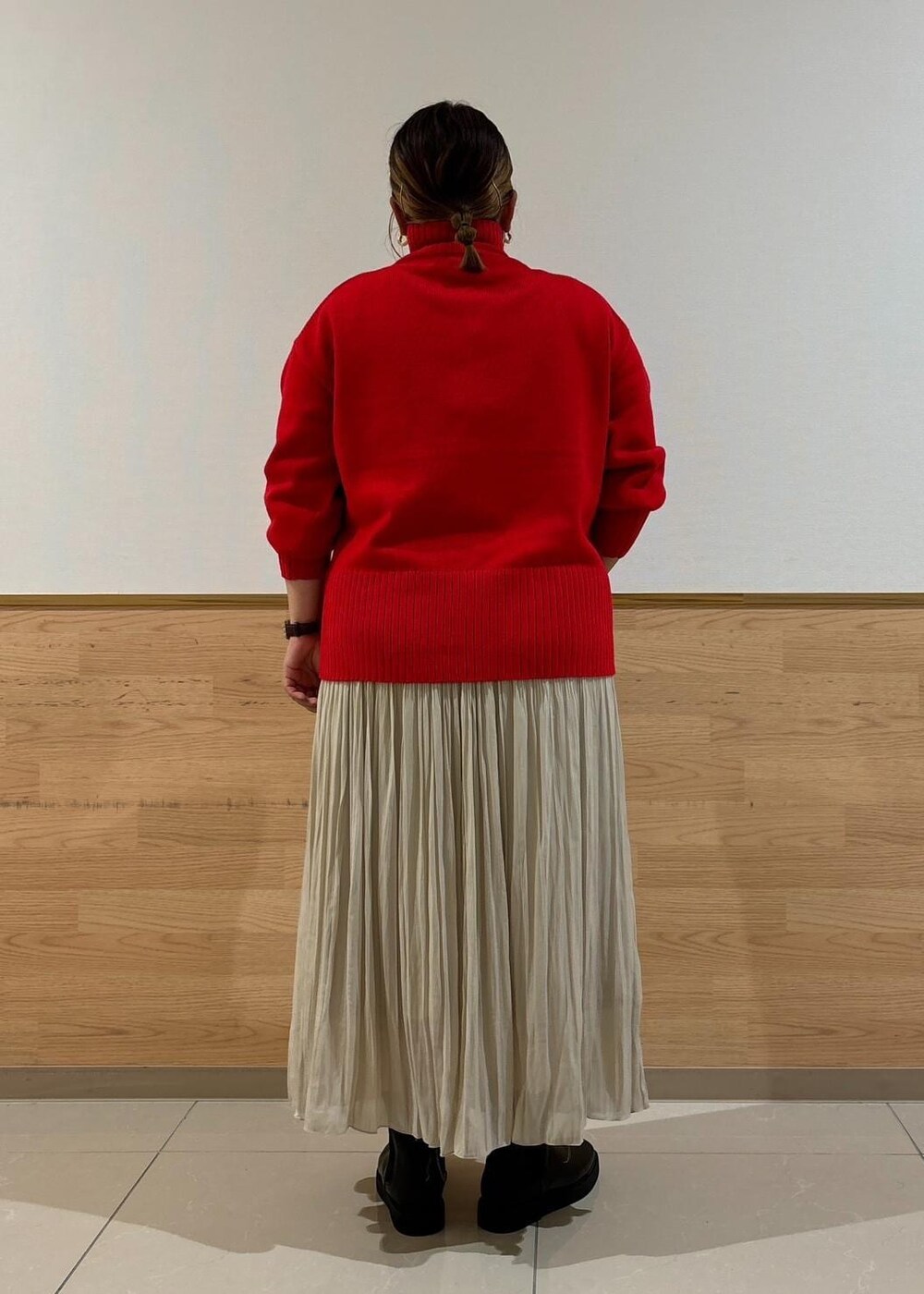 レッド系のニット/セーター、ベージュ系のスカート、ブラック系のブーツを着用したレディースの秋コーディネートの3枚目の写真