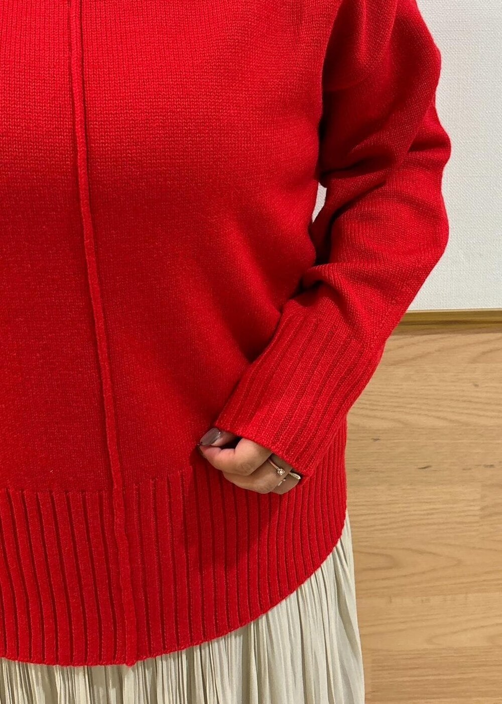 レッド系のニット/セーター、ベージュ系のスカート、ブラック系のブーツを着用したレディースの秋コーディネートの5枚目の写真