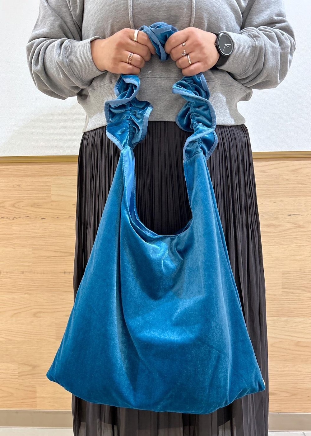 ブルー系のショルダーバッグ、ブラウン系のスカート、グレー系のパーカーを着用したレディースの秋コーディネートの9枚目の写真