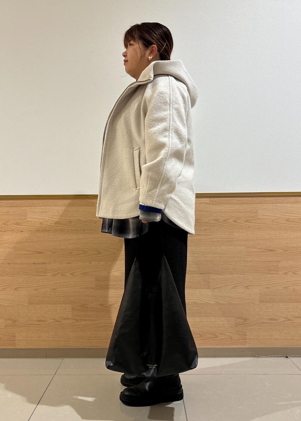 ブラック系のスカート、ブラック系のトートバッグ、ブルー系のニット/セーターを着用したレディースの秋コーディネートの2枚目の写真