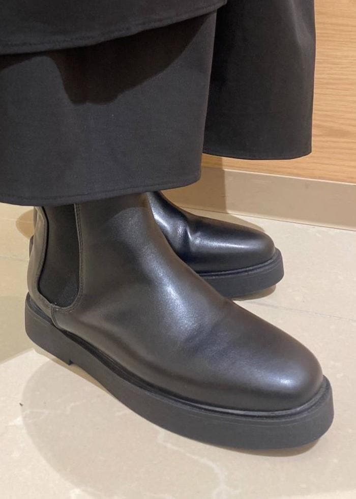 ブラック系のスカート、ブラック系のブーツ、グレー系のショルダーバッグを着用したレディースの冬コーディネートの9枚目の写真