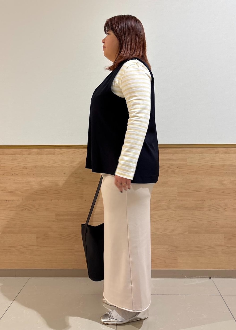 ベージュ系のスカート、ベージュ系のTシャツ/カットソー、ブルー系のベストを着用したレディースの冬コーディネートの2枚目の写真