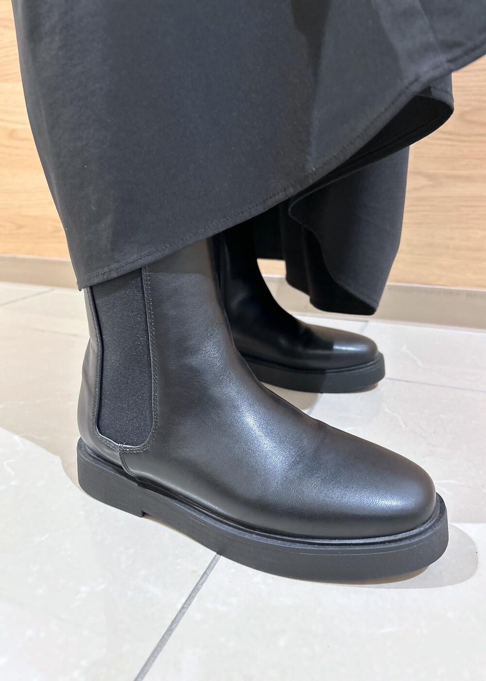 ブラック系のスカート、ブラック系のブーツ、シルバー系のショルダーバッグを着用したレディースの秋コーディネートの8枚目の写真