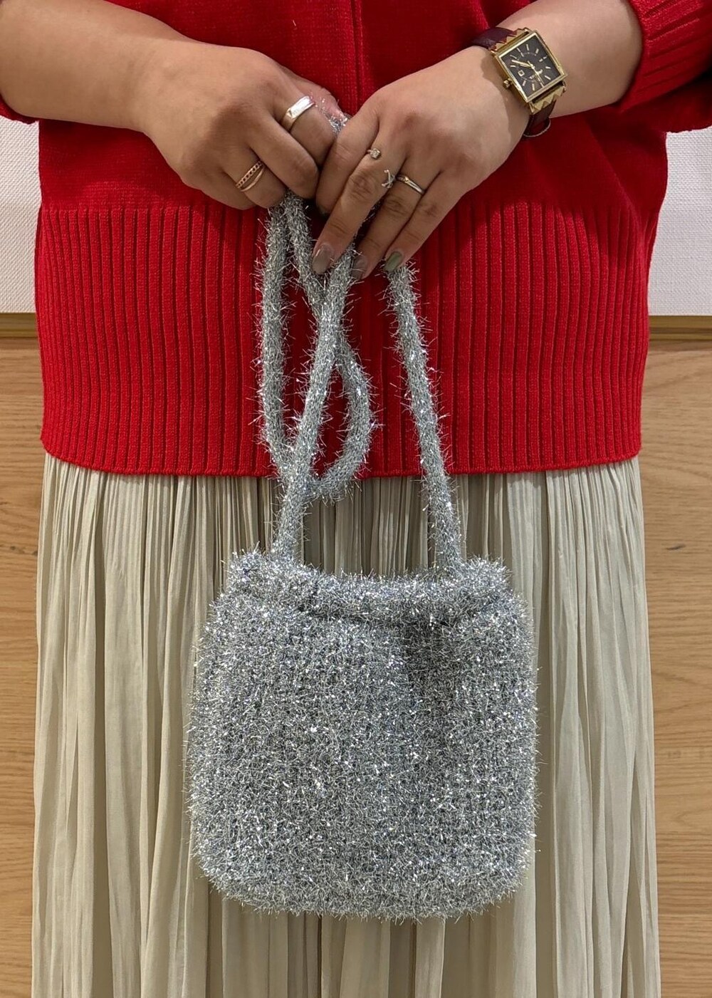 レッド系のニット/セーター、ベージュ系のスカート、ブラック系のブーツを着用したレディースの秋コーディネートの7枚目の写真