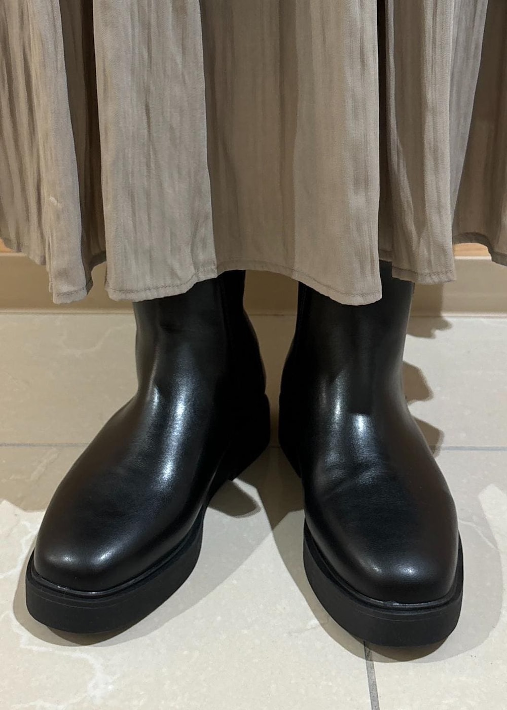 ホワイト系のTシャツ/カットソー、ブラック系のブーツ、ブラウン系のスカートを着用したレディースの秋コーディネートの8枚目の写真