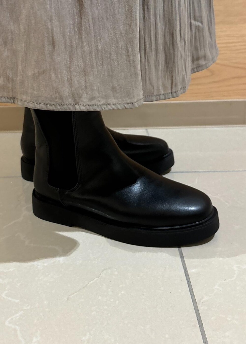 ホワイト系のTシャツ/カットソー、ブラック系のブーツ、ブラウン系のスカートを着用したレディースの秋コーディネートの9枚目の写真