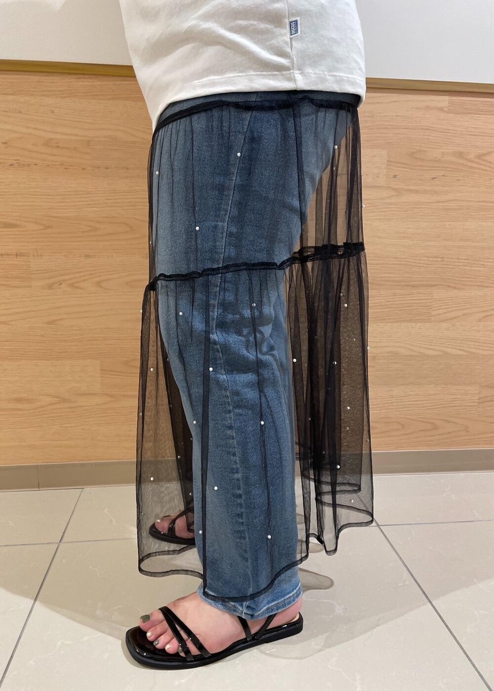 ブラック系のスカート、ブラック系のサンダル、ホワイト系のTシャツ/カットソーを着用したレディースの夏コーディネートの6枚目の写真