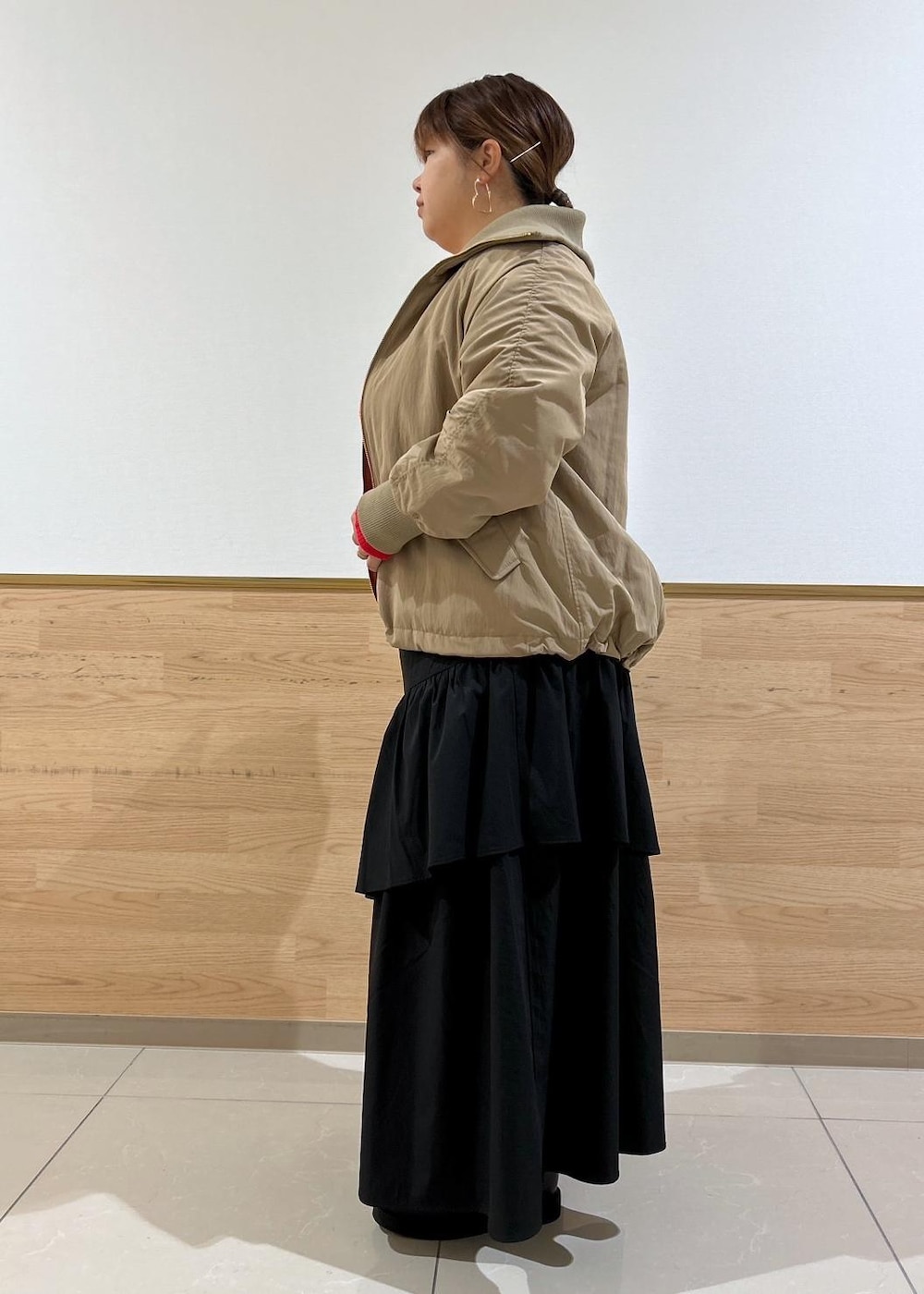 ブラック系のスカート、ブラック系のブーツ、シルバー系のショルダーバッグを着用したレディースの秋コーディネートの2枚目の写真