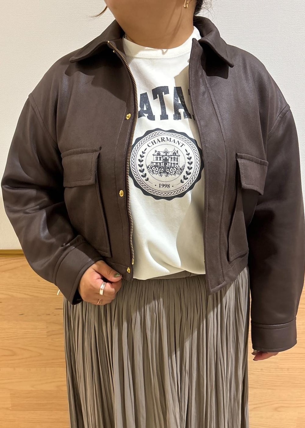 ホワイト系のTシャツ/カットソー、ブラック系のブーツ、ブラウン系のスカートを着用したレディースの秋コーディネートの4枚目の写真