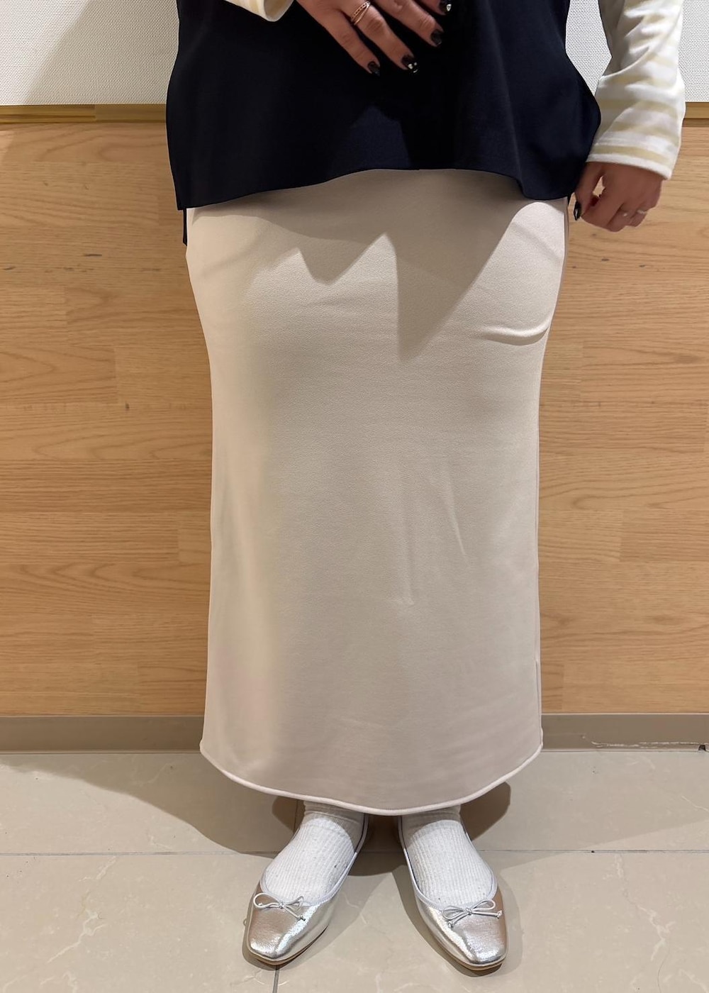 ベージュ系のスカート、ベージュ系のTシャツ/カットソー、ブルー系のベストを着用したレディースの冬コーディネートの6枚目の写真