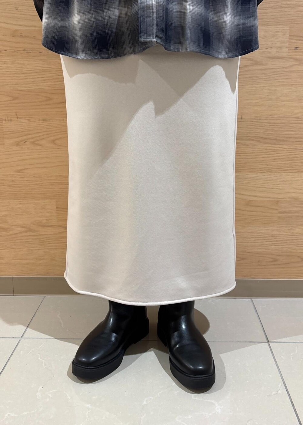 ベージュ系のスカート、ブルー系のニット/セーター、ブラック系のブーツを着用したレディースの冬コーディネートの7枚目の写真