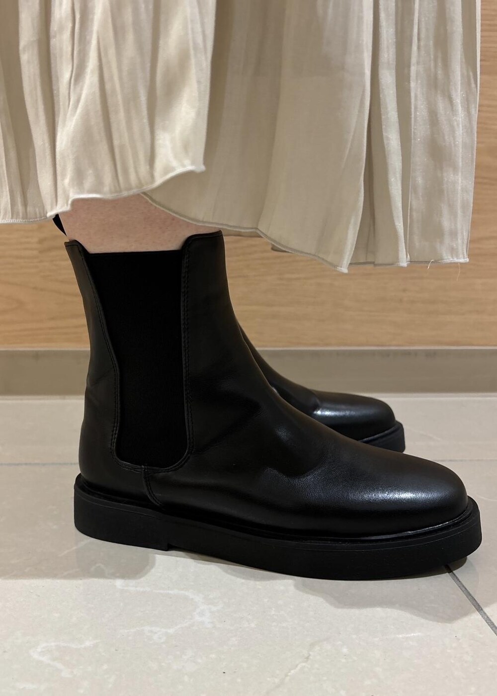 レッド系のニット/セーター、ベージュ系のスカート、ブラック系のブーツを着用したレディースの秋コーディネートの10枚目の写真