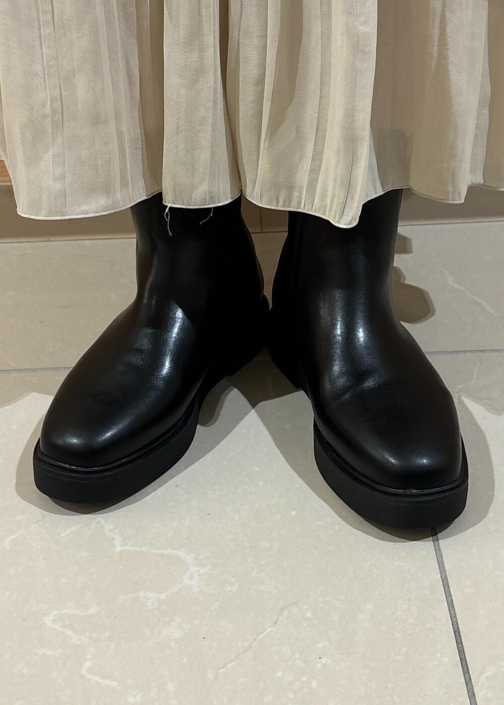 レッド系のニット/セーター、ベージュ系のスカート、ブラック系のブーツを着用したレディースの秋コーディネートの9枚目の写真