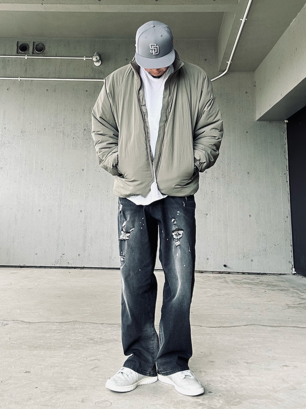 グリーン系のブルゾン、ホワイト系のTシャツ/カットソー、ブラック系のデニムパンツを着用したメンズの春コーディネートの3枚目の写真