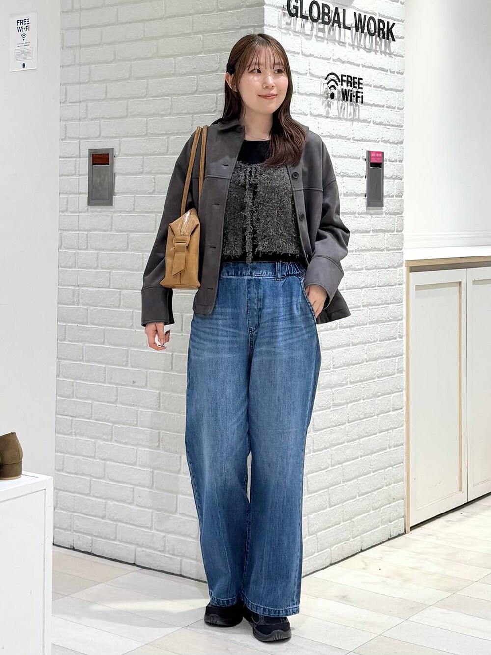 ブラウン系のボストンバッグ、ブルー系のデニムパンツ、グレー系のテーラードジャケットを着用したレディースの冬コーディネートの4枚目の写真